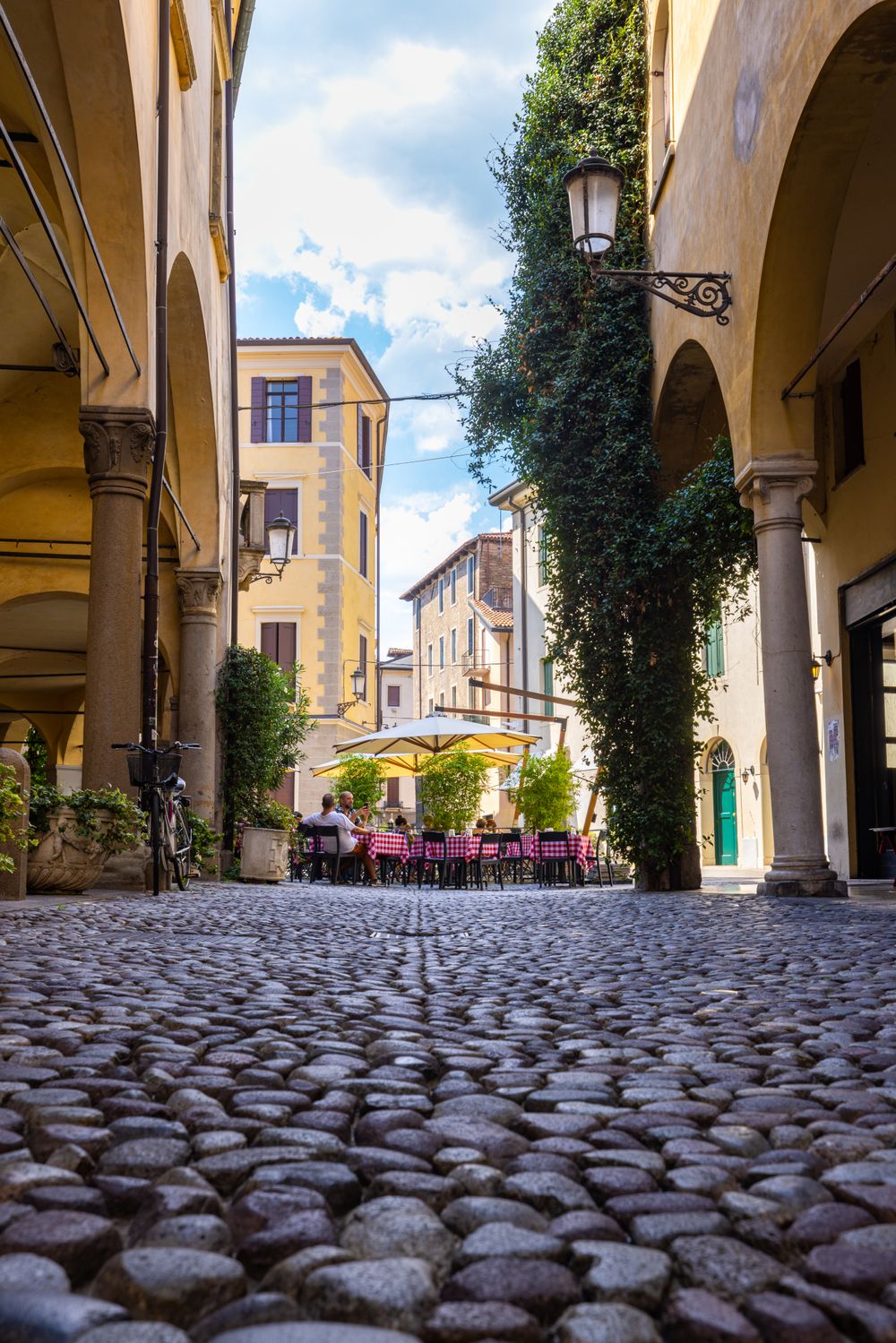 Outdoor café tables along a cobblestone street in Italy